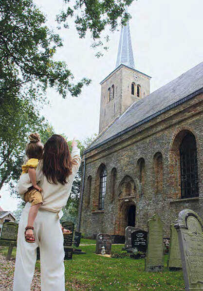 Een vrouw met kind kijken naar de Johanneskerk in Weidum