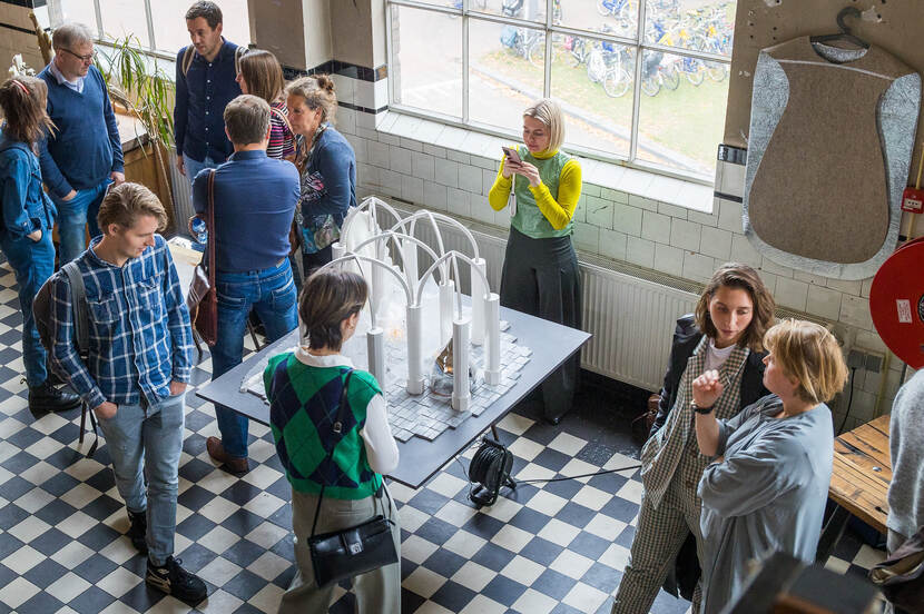 Bezoekers bekijken een witte maquette van een kerkgebouw